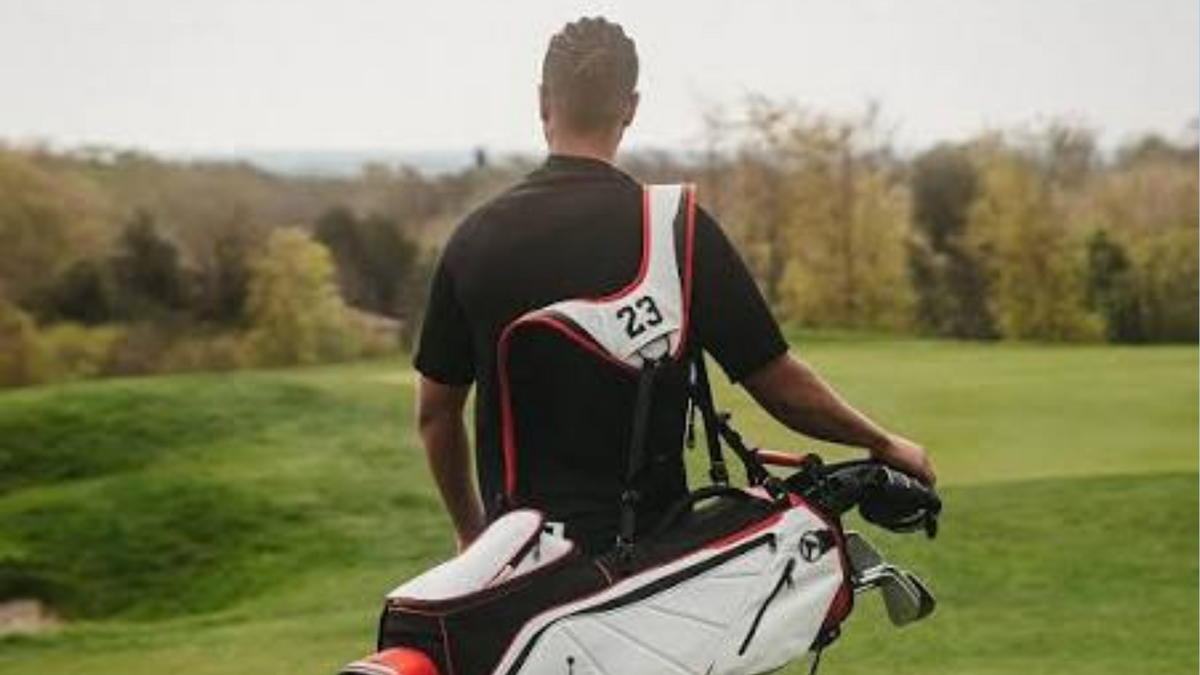 Golfer seen from behind in a black top, carrying a white, black and red Jordan golf bag with 23 on the strap