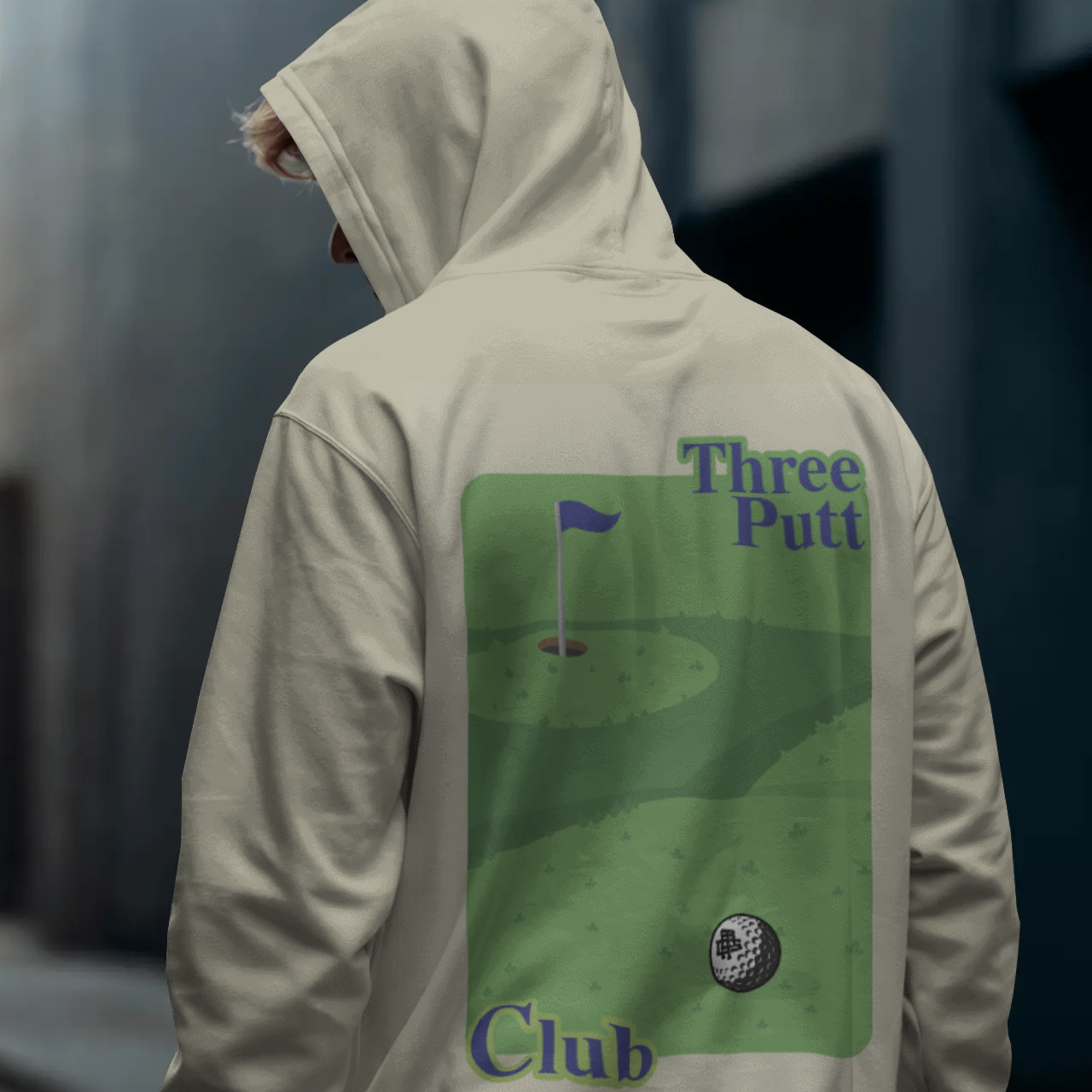 Person wearing a hoodie with 'Three Putt Club' graphic on the back, standing in an urban setting.