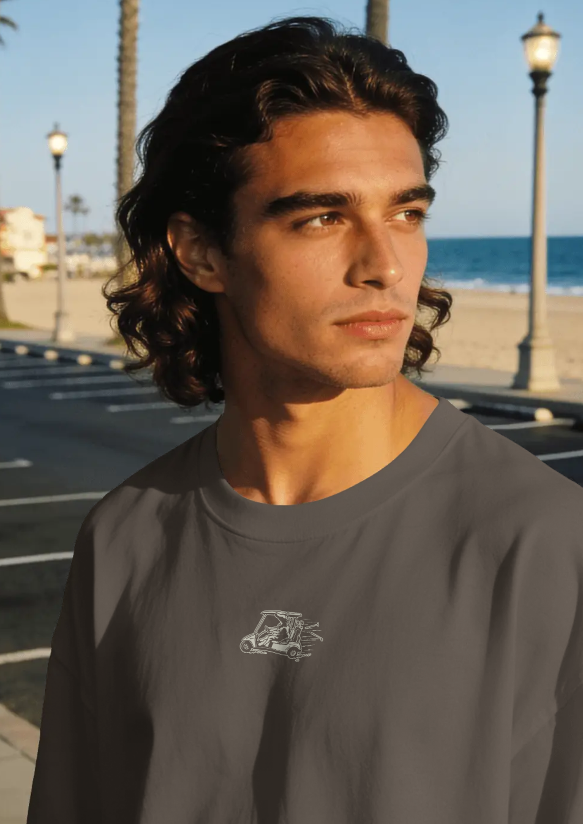 Man by the sea wearing the Reckless Driving golf T-shirt in Black, with the cow-and-golf-cart print on the chest