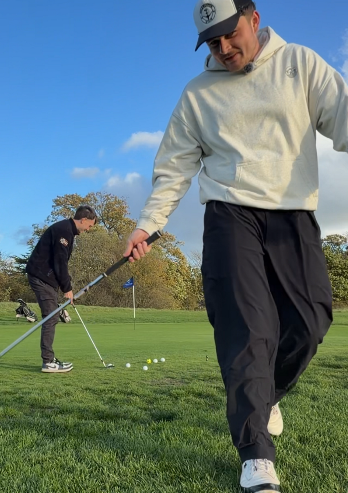 Golfer walking off the practice green in the Contours golf hoodie, front view with the round cow badge on the chest