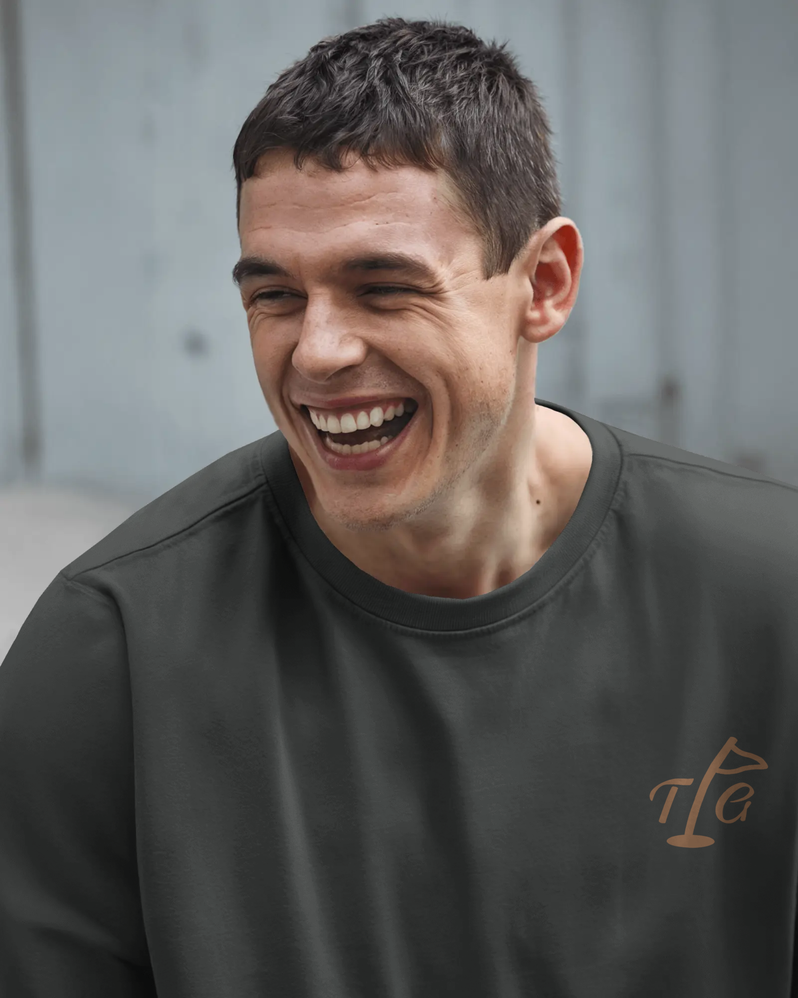 Male model seated wearing Three Putt Golf Streetwear T-Shirt in Dark Gray with TPG logo on left chest