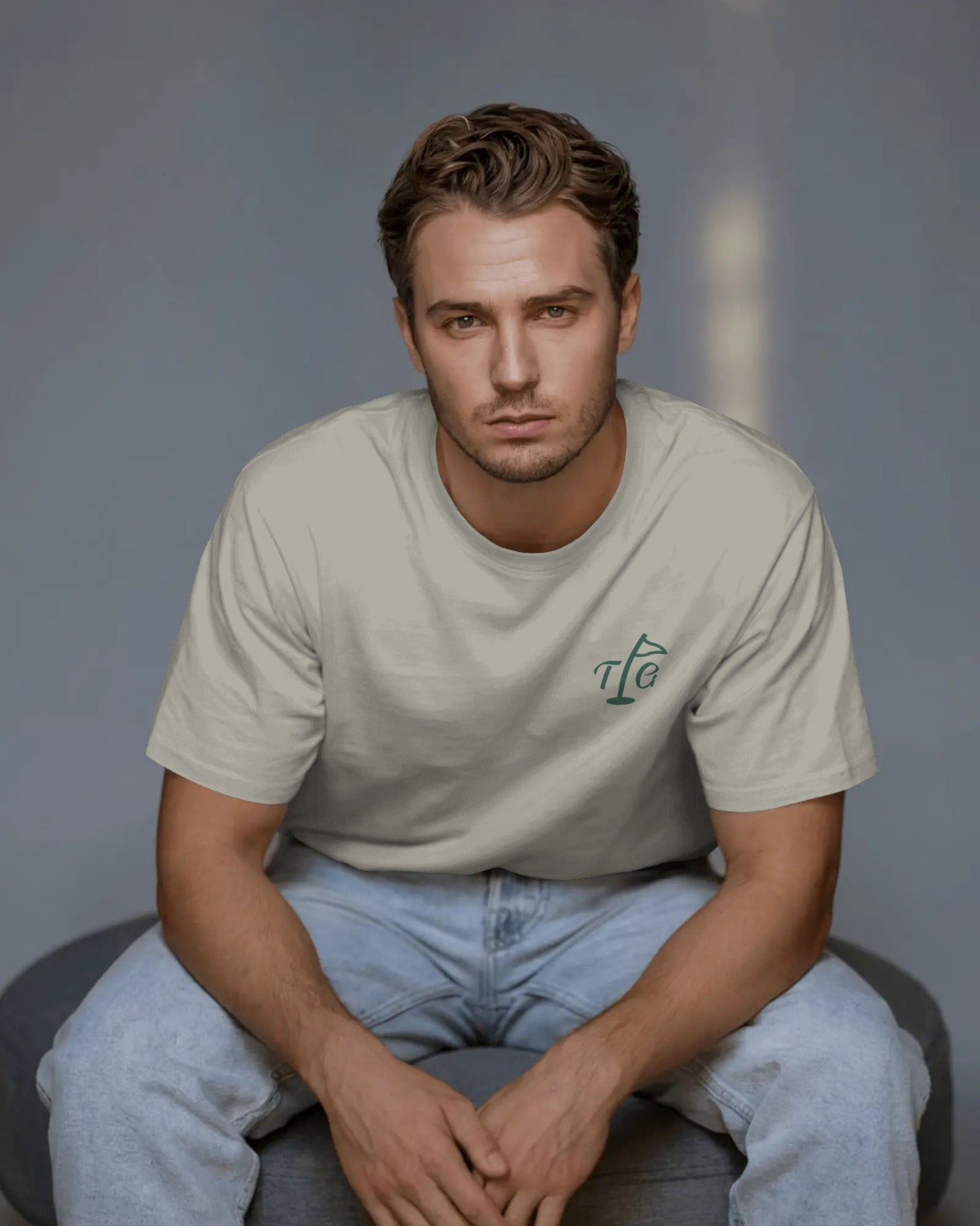 Male model sitting in Three Putt Golf Streetwear T-Shirt in Apricot, relaxed oversized fit