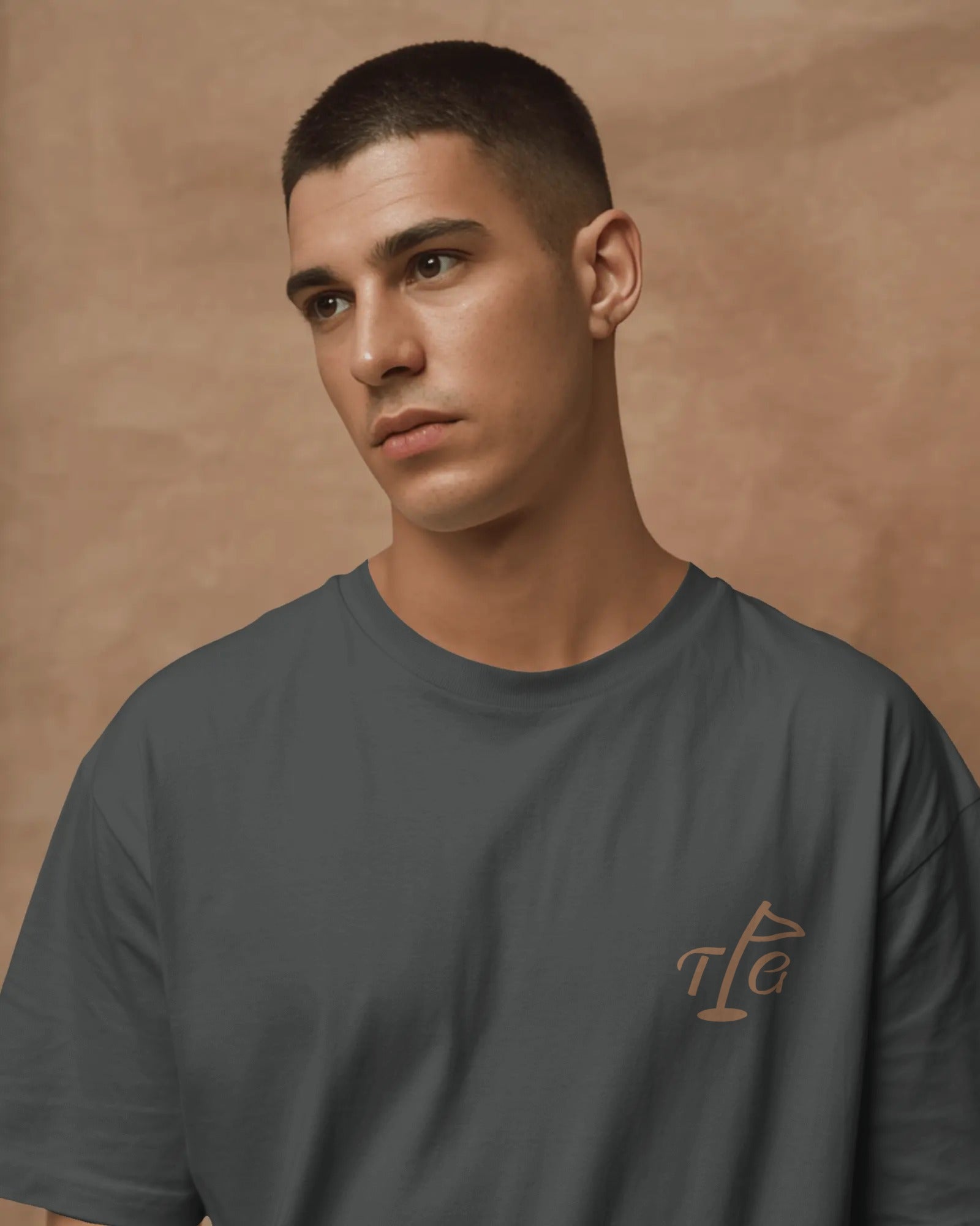 Male model standing wearing Three Putt Golf Streetwear T-Shirt in Dark Gray with TPG logo on left chest