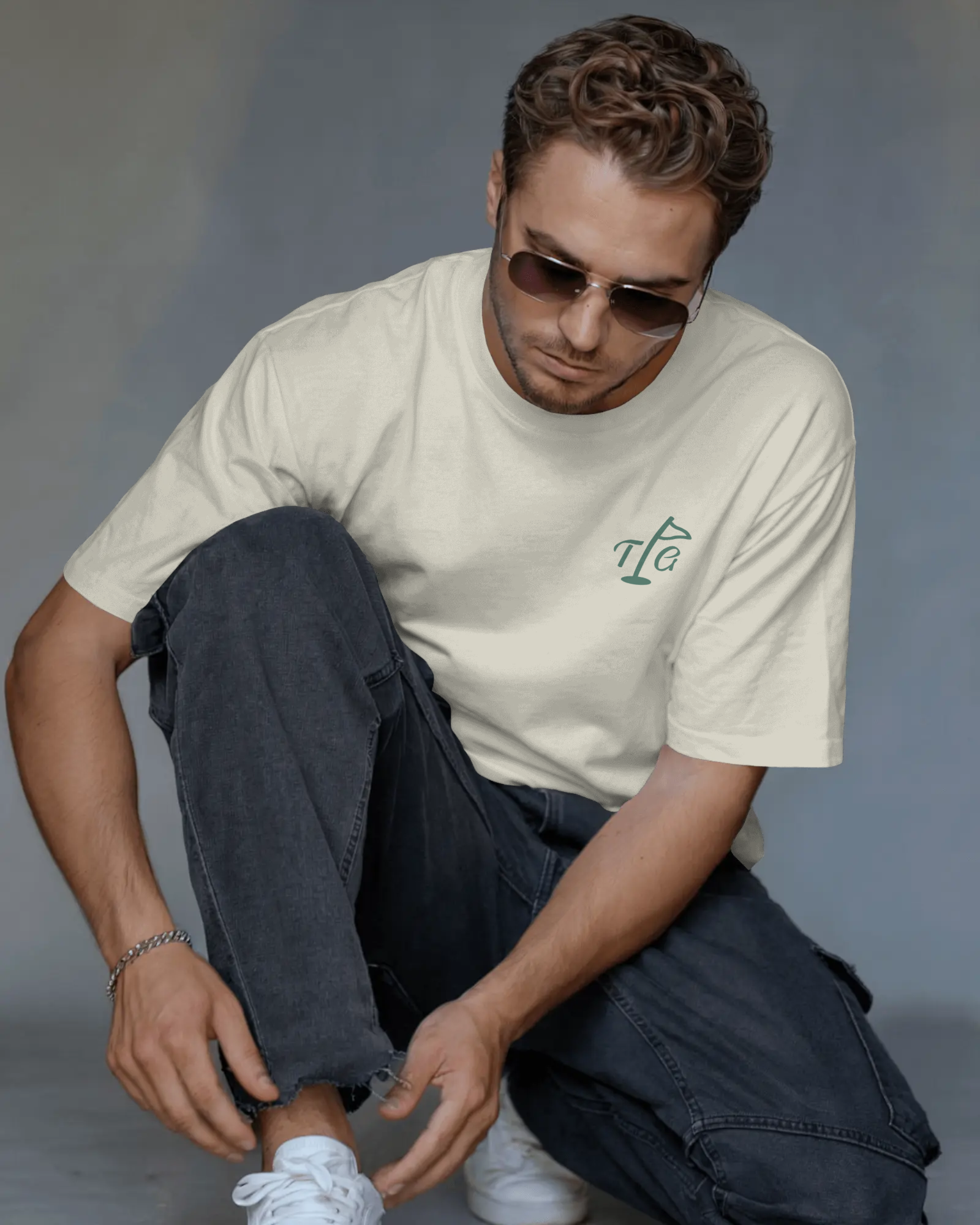 Male model wearing Three Putt Golf Streetwear T-Shirt in Apricot, tying shoelace