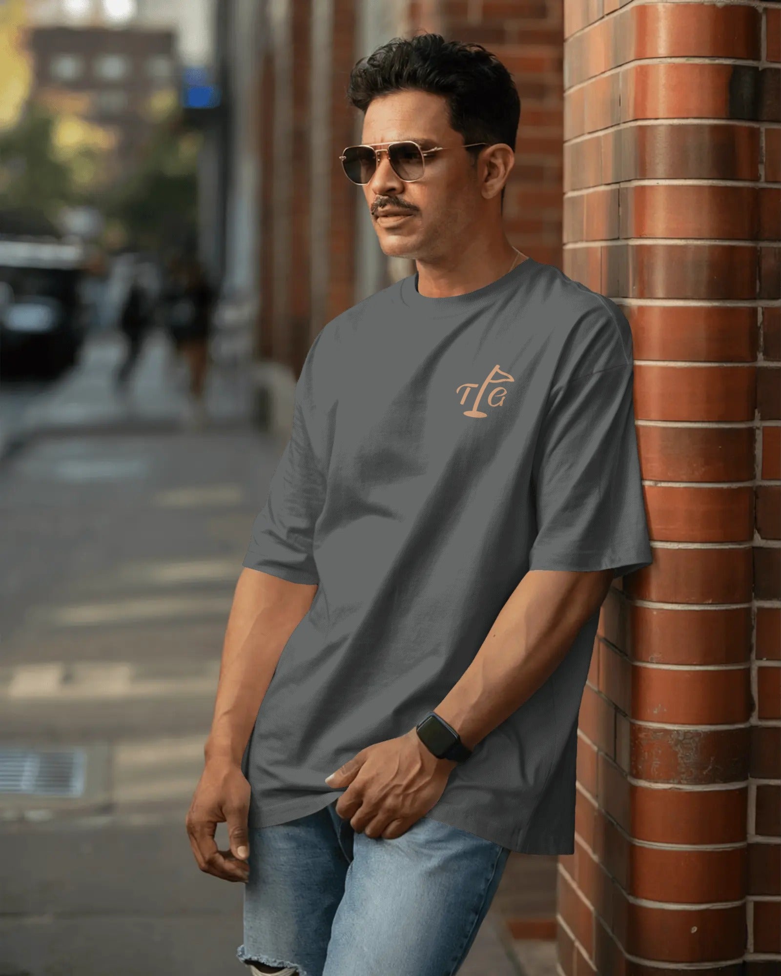 Male model wearing Three Putt Golf Streetwear T-Shirt in Dark Grey, outdoor brick wall setting