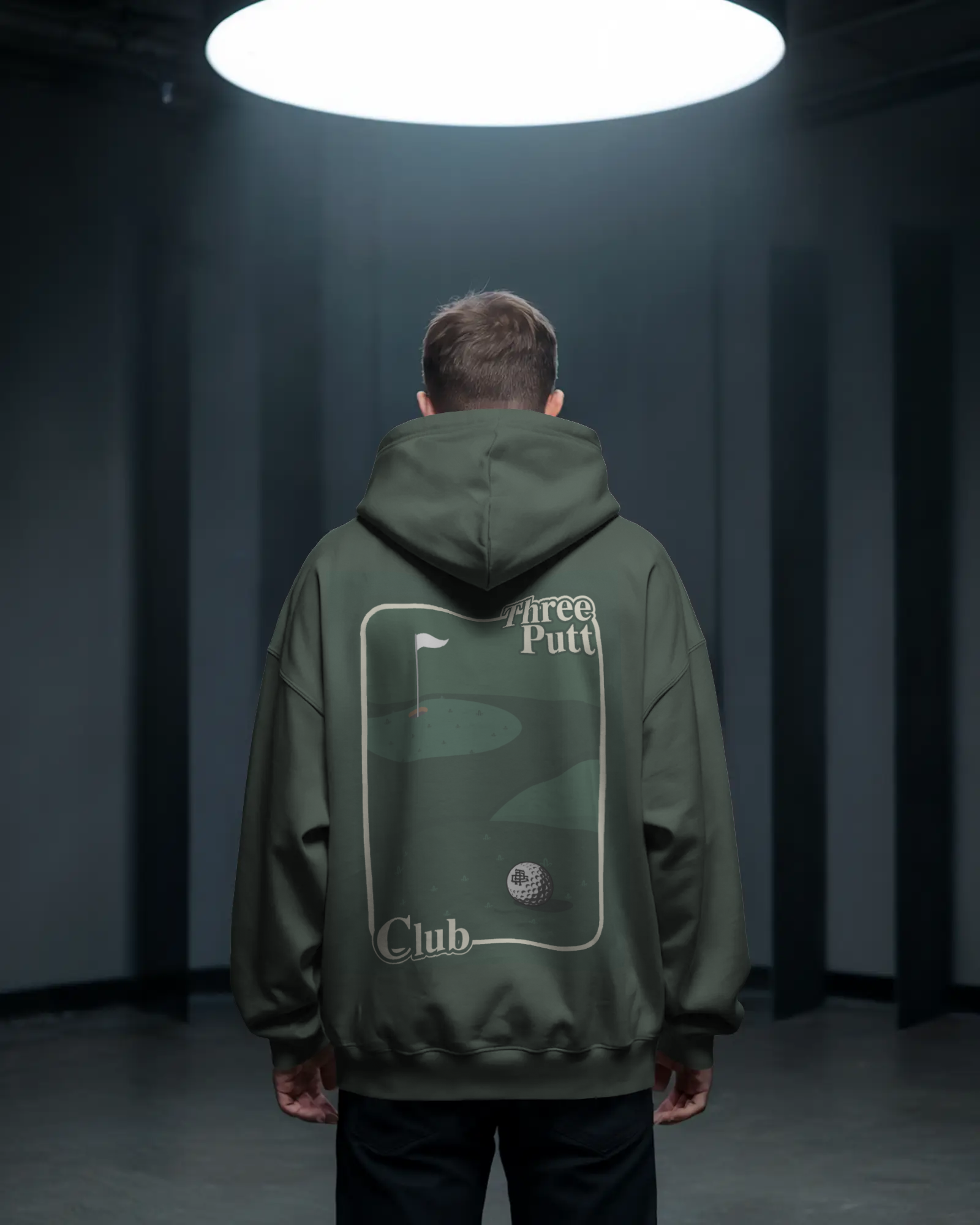 Person wearing a green hoodie with 'Three Putt Club' logo in a dark room.