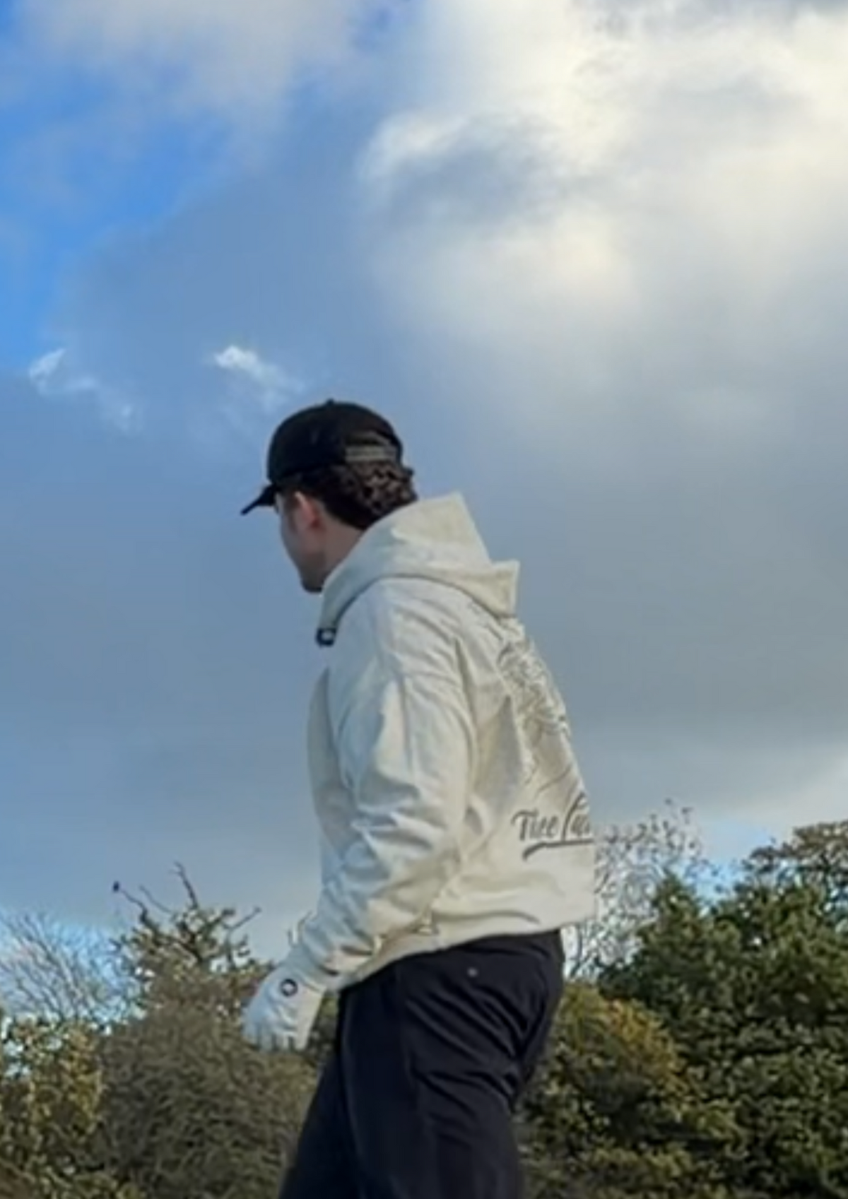Golfer in the Contours golf hoodie looking out over the course, with the Three Putt Golf script on the back